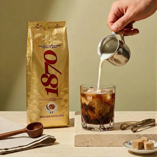 Caffè Barbera 1870 Mago whole bean coffee bag next to an iced latte with milk being poured over ice