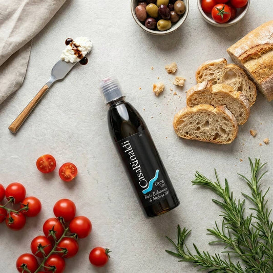 Casa Rinaldi Balsamic Glaze of Modena PGI 250ml bottle with cherry tomatoes, ricotta on bread, olives, and fresh rosemary