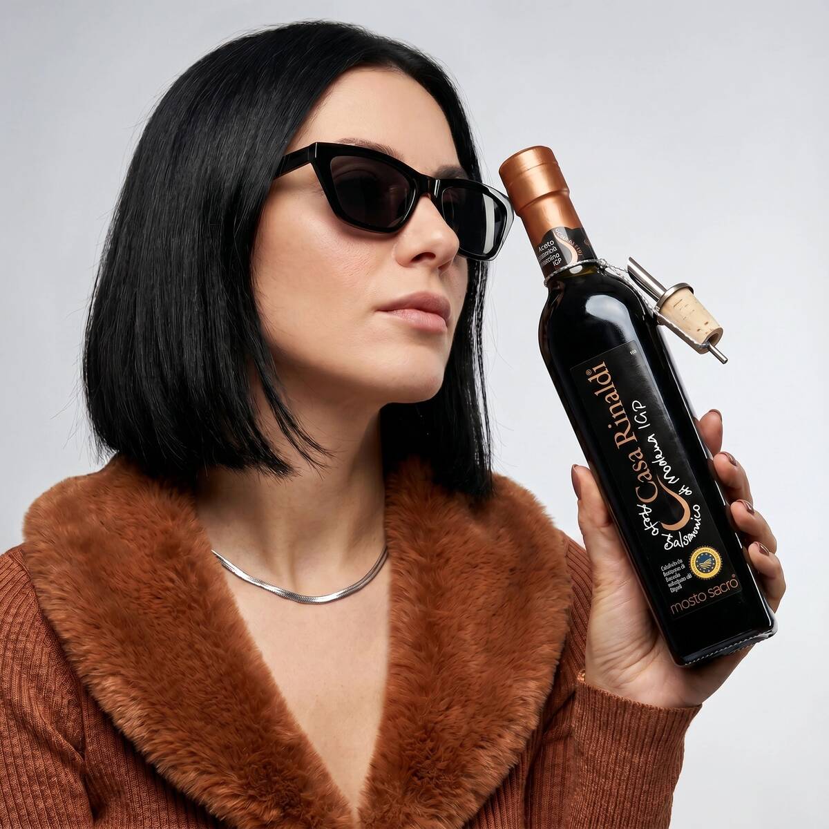 Woman holding a bottle of Casa Rinaldi Mosto Sacro Balsamic Vinegar of Modena PGI, 250ml